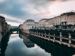 A canal with buildings on either side, a bridge, and a clear sky.