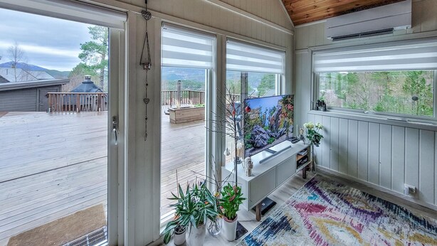 Una habitación amplia con ventanas grandes, techo de madera y vistas al exterior.