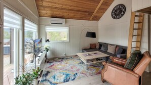 Una sala de estar acogedora con techo de madera, un sofá, una mesa de centro y un reloj en la pared.
