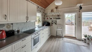 Una cocina moderna con armarios blancos, estufa negra y techo de madera.