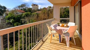 Un balcón con una mesa y sillas, con vistas a casas y árboles.