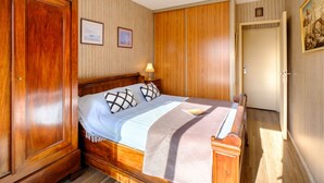 Un dormitorio con una cama de madera, una mesita de noche, un armario y una puerta.
