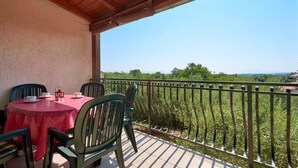Ein Balkon mit Tisch und Stühlen, der einen üppigen, grünen Landschaftsblick bietet.