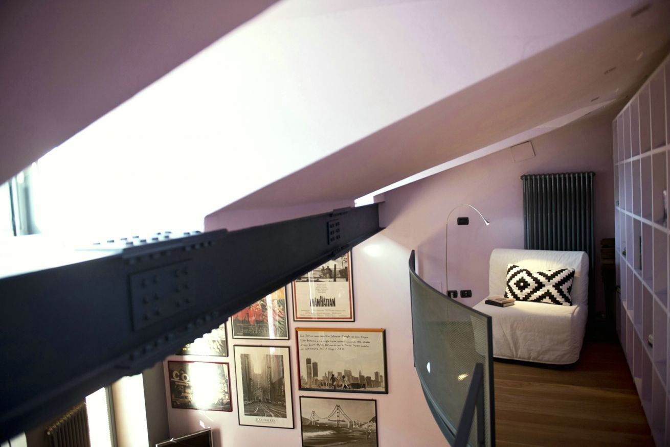 A modern interior with a glass partition, a white sofa with a patterned pillow, and framed cityscape photographs on the wall.