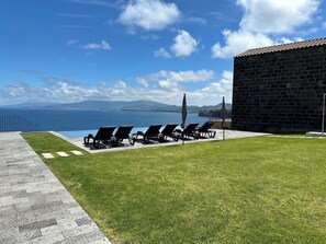 Een buitenzwembad, parasols bij het zwembad en ligstoelen