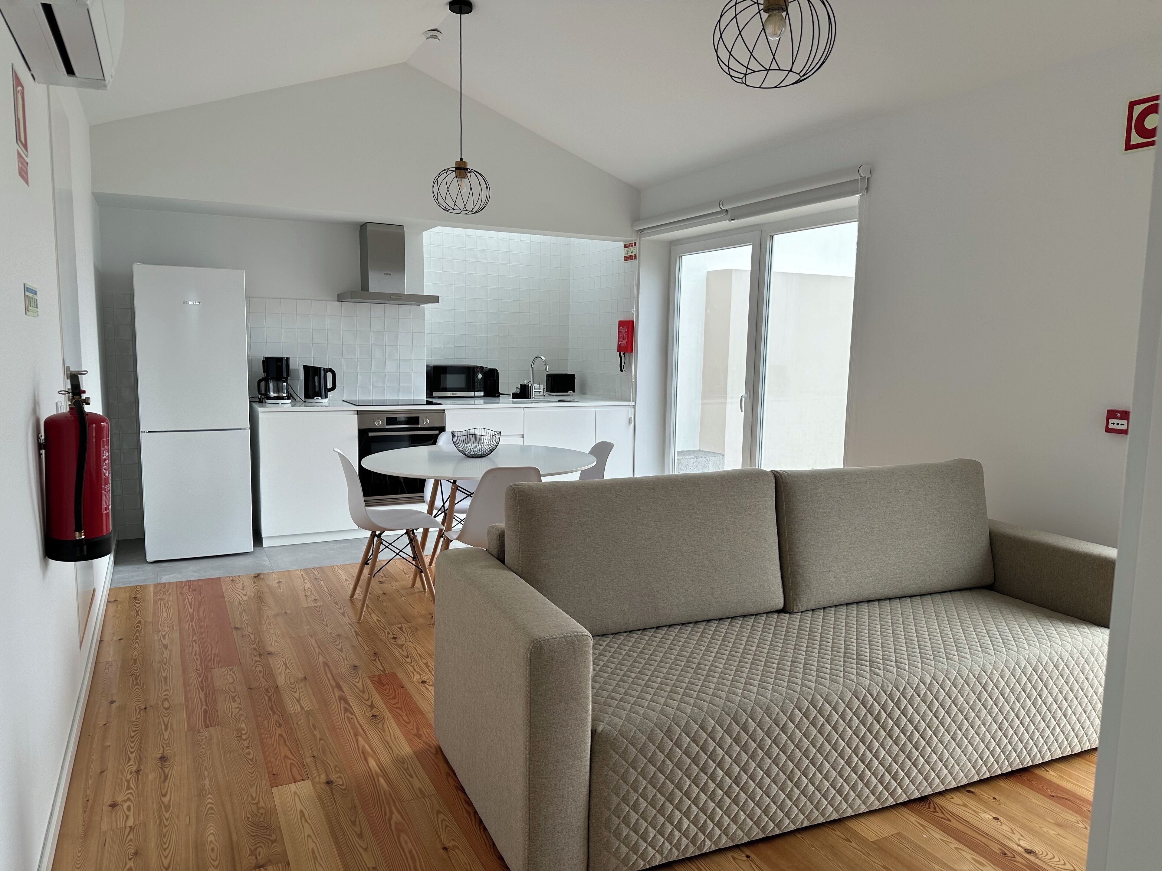 A modern apartment with a kitchenette, a dining area, and a living room with a sofa.