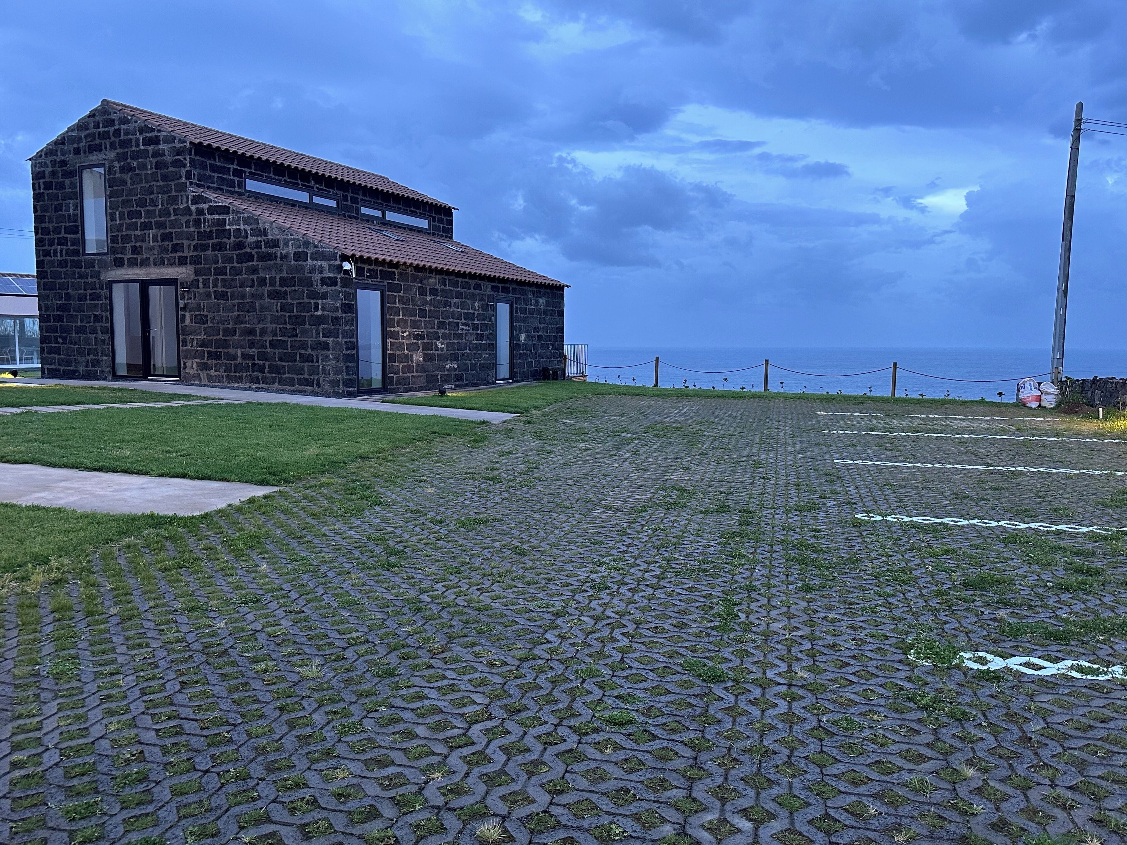A stone building with a tiled roof and a paved area with grass patches.