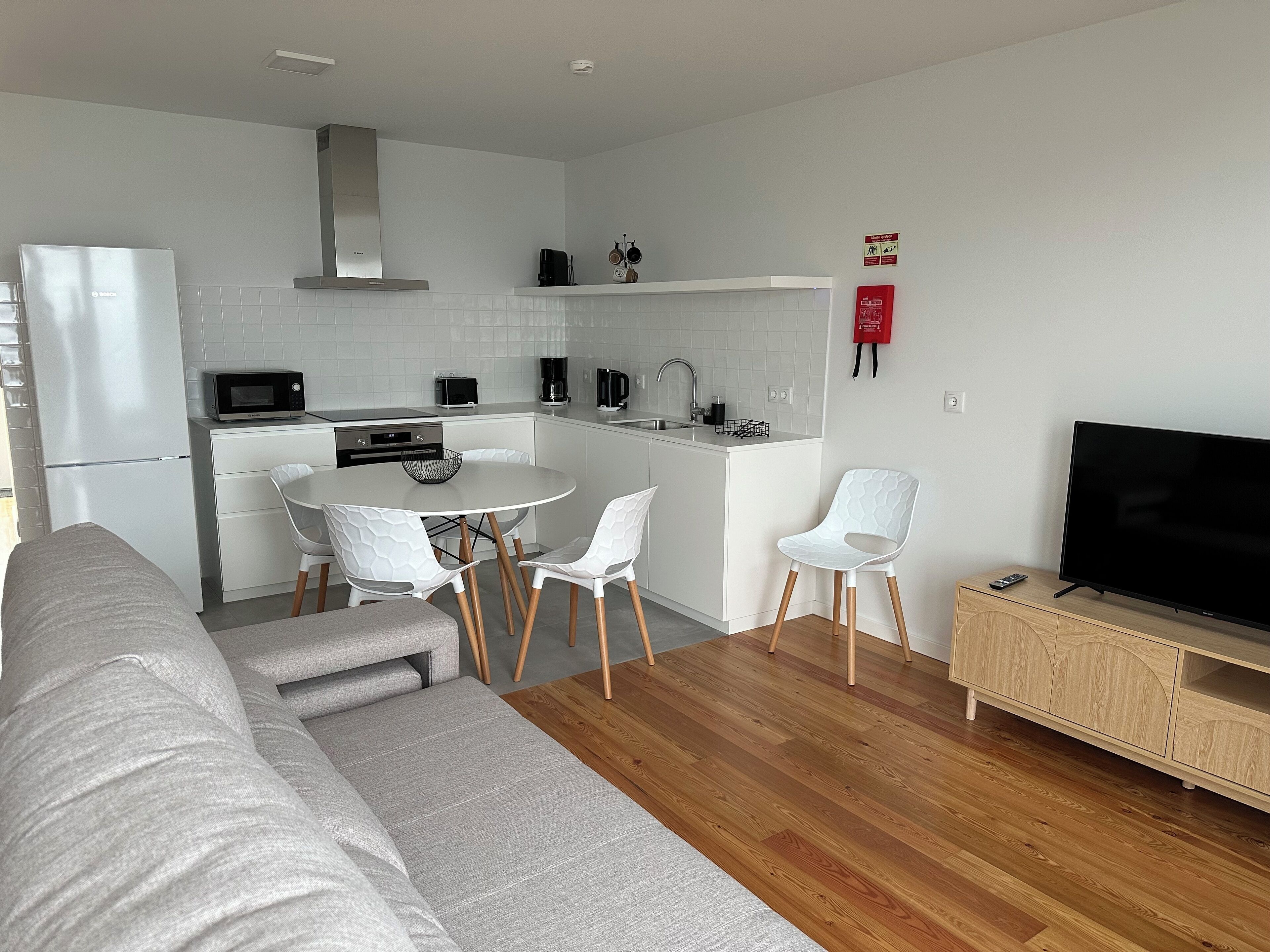 A modern kitchen with white cabinets, a Bosch refrigerator, a microwave, and a coffee maker.