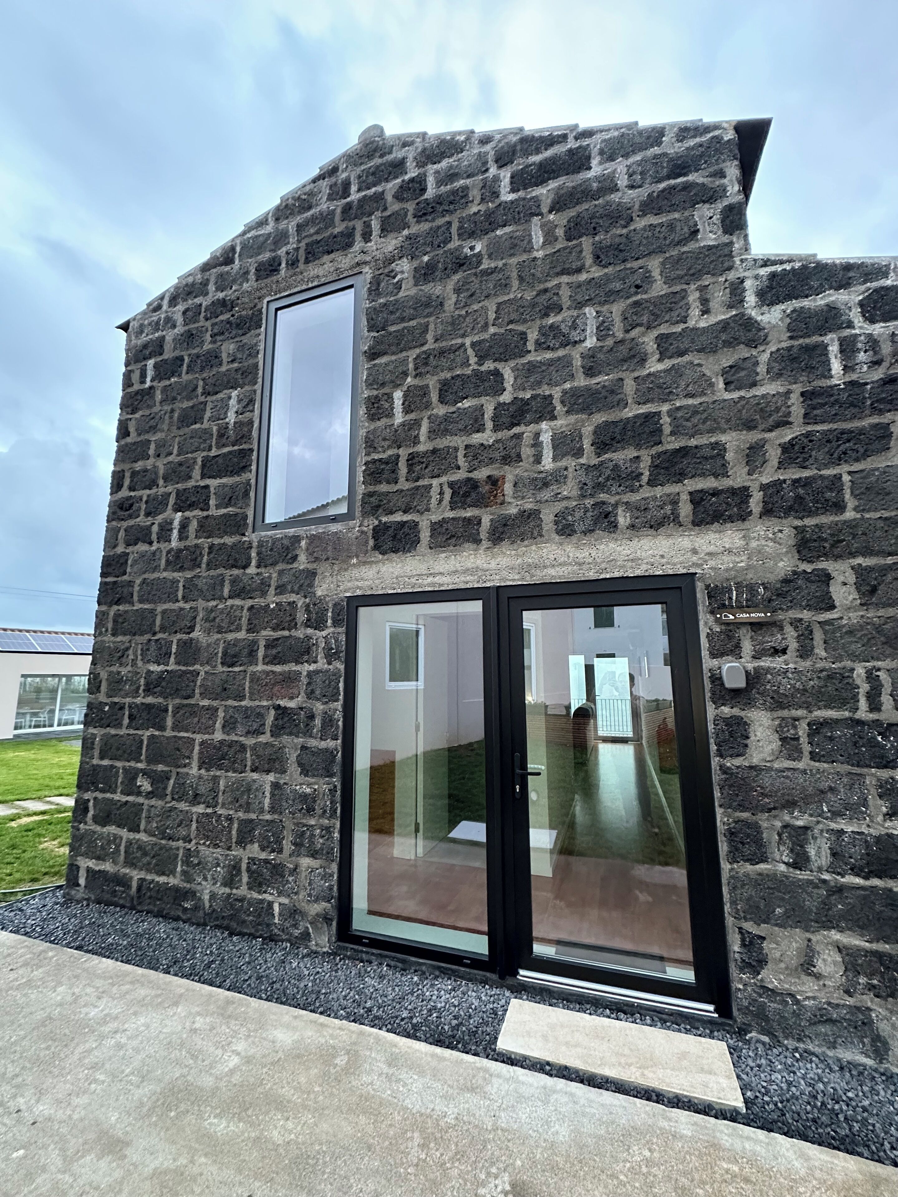A modern building with a stone facade, a large glass door, and a small window.