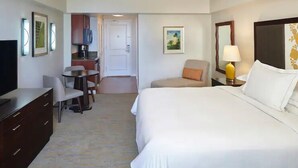 A hotel room with a bed, a desk, a chair, a TV, and a lamp. - Waikiki | Couples Surf Nest | Pool + Spa (Honolulu)