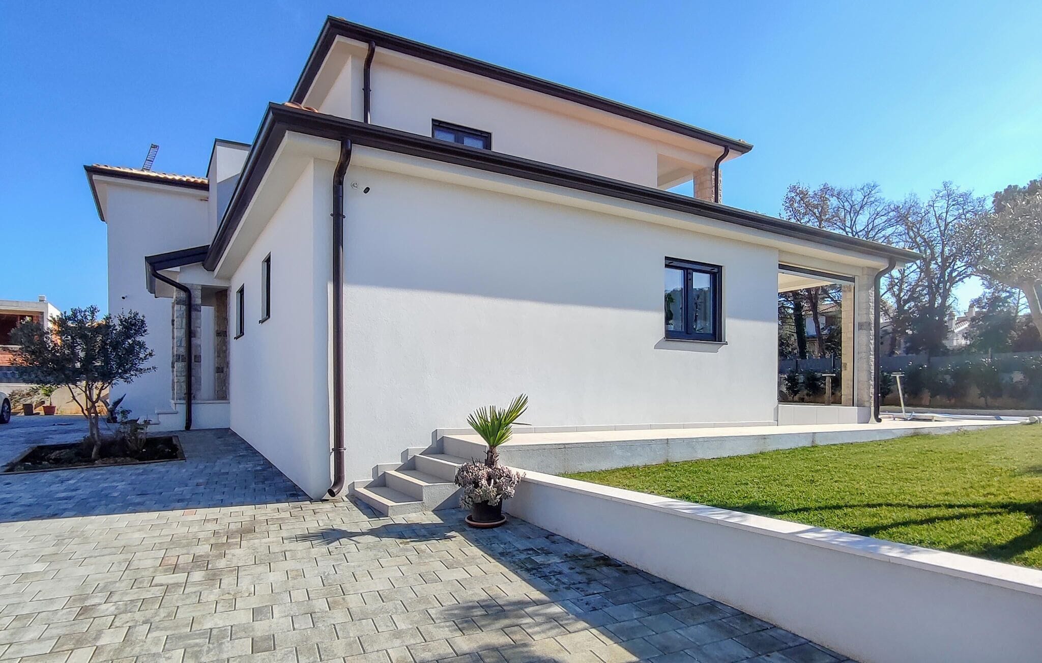 A modern two-story house with a white exterior, a small front porch, and a well-maintained lawn.