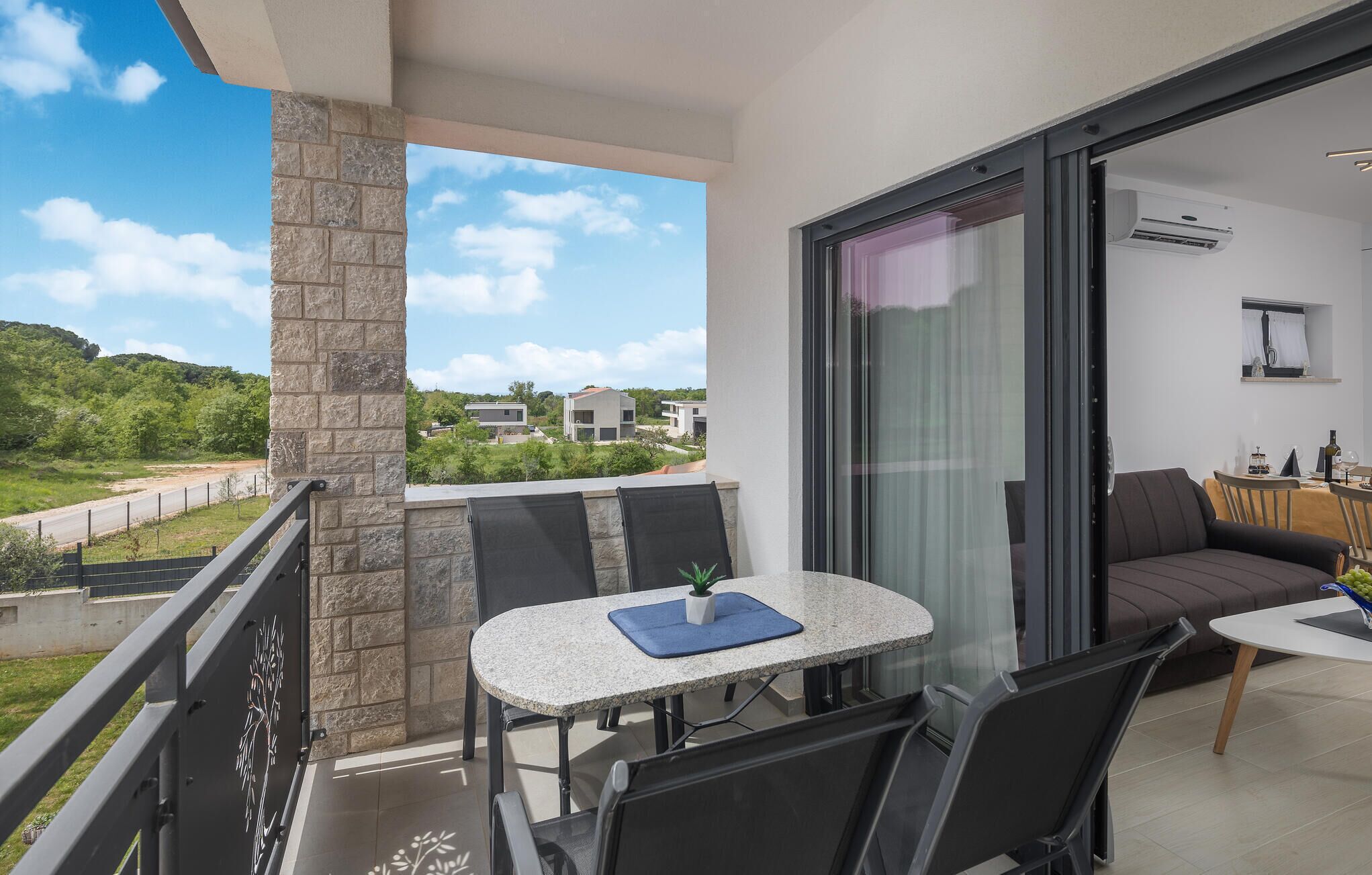 Un balcon avec une table et des chaises, un canapé et une vue sur un quartier résidentiel.