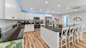Una cocina moderna con armarios blancos, encimera negra y suelo de madera.