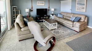 Ein Wohnzimmer mit Sofa, Sesseln, Couchtisch, Fernseher und Dekoration.