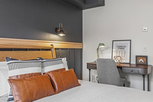 A hotel room with a bed, a desk, a chair, and a wall-mounted lamp. - W118 Canmore King Room- A/C, Central, Free parking, Gym, Free Disney+, HBO (Canmore)