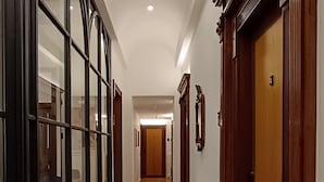 A hallway with a patterned rug, wooden doors, and a table with chairs. - Deluxe Spaccanapoli (Naples)