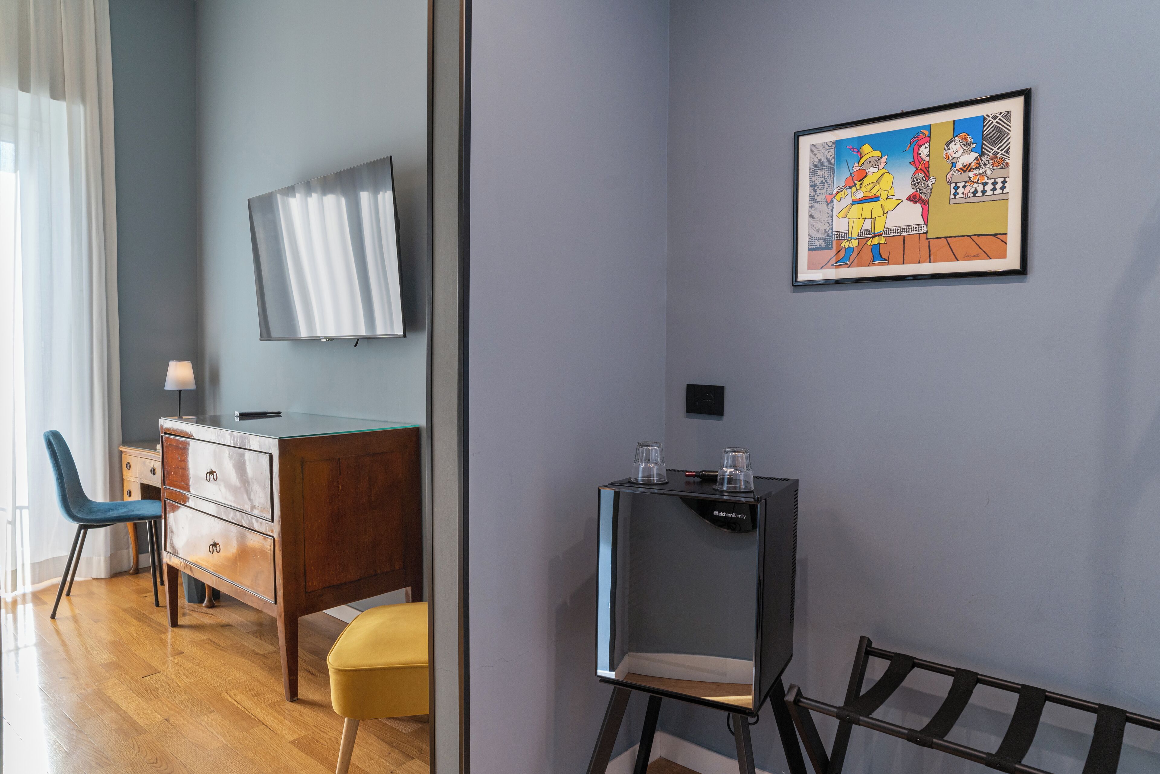 A modern room with a wooden desk, a chair, a television, and a framed artwork on the wall.