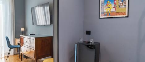 A modern room with a wooden desk, a chair, a television, and a framed artwork on the wall.