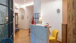A reception area with a desk, chairs, and a decorative wall. - Deluxe Spaccanapoli (Naples)