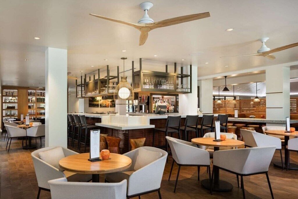 A modern restaurant with round tables, bar seating, and a central bar area.