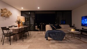 Una sala moderna con comedor, un sofá, un televisor y vistas a la ciudad.