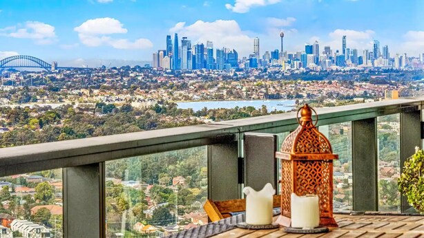 Un balcón con vista a un horizonte urbano, incluyendo un puente y edificios altos.