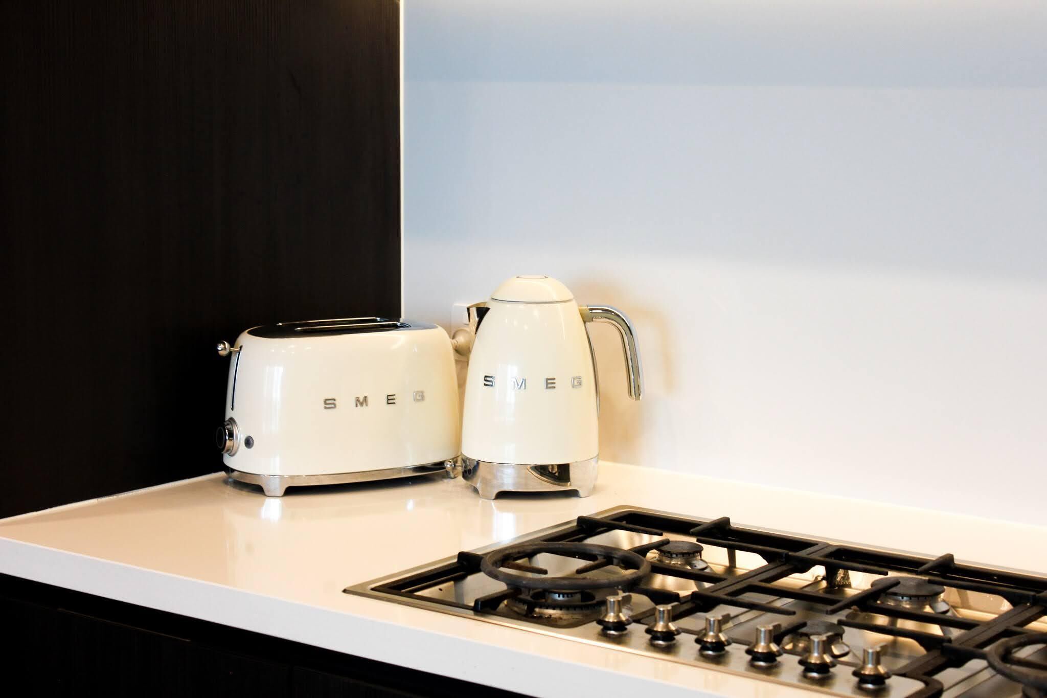Une cuisine avec un plan de travail blanc, un grille-pain et une bouilloire.