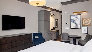 A modern hotel room with a bed, a TV, a desk, and a chair. - Charleston | Couples Historic Retreat | Gym + Downtown (Charleston)