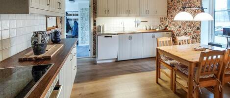 A kitchen with wooden cabinets, a central island, and a dining area with a table and chairs.