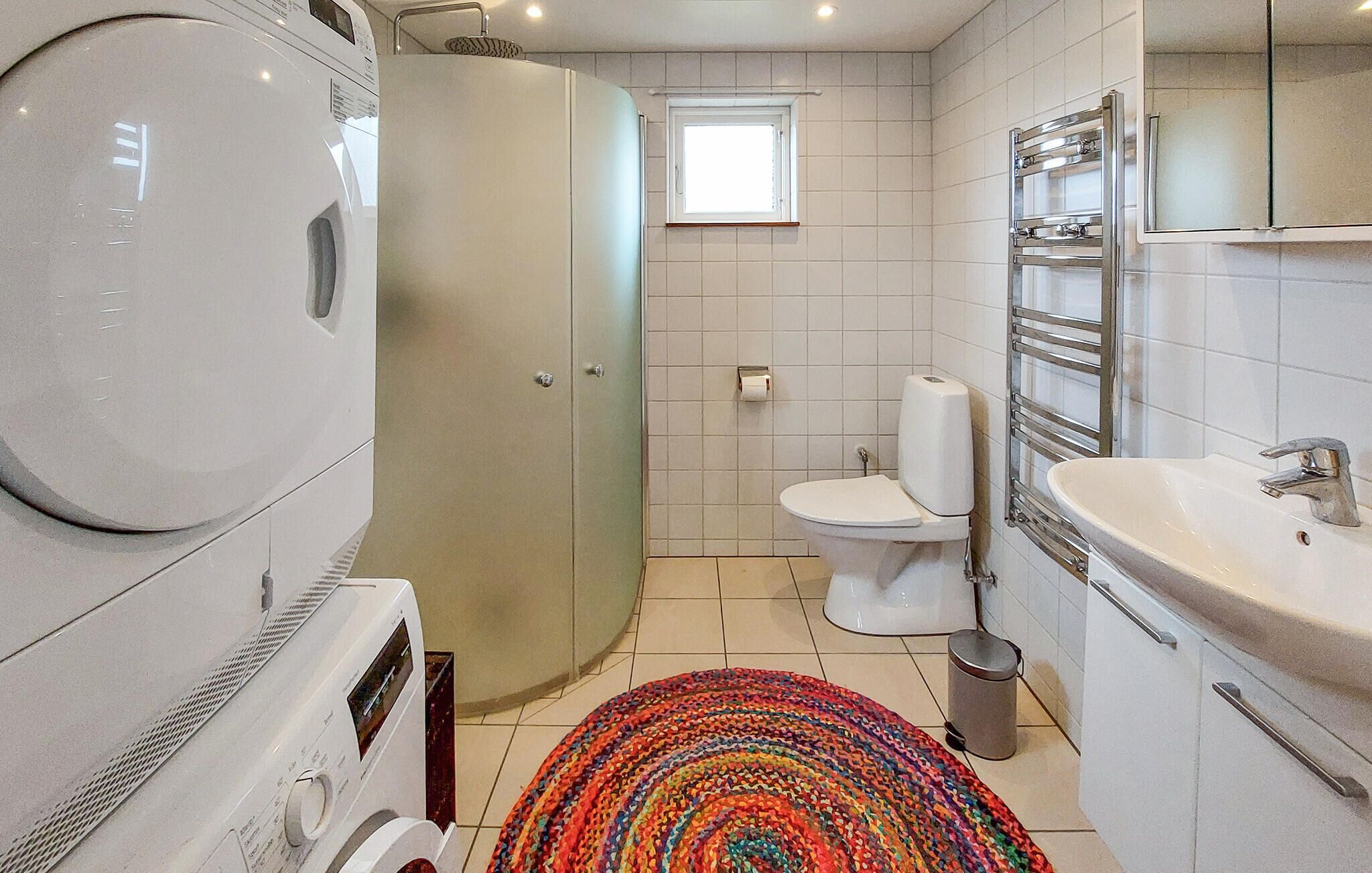 A compact bathroom with a washing machine, toilet, and sink.