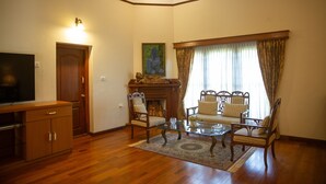 Een woonkamer met een houten vloer, een zithoek, een glazen salontafel, een televisie en een open haard.