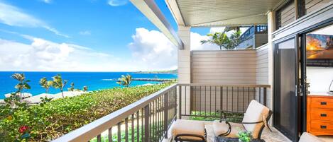 A balcony with a view of the ocean, outdoor furniture, and a sliding glass door.