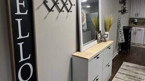 Ein Flur mit einem großen Spiegel, einem an der Wand befestigten Schild mit der Aufschrift "oh HELLO there" und einer kleinen Pflanze auf der Theke.