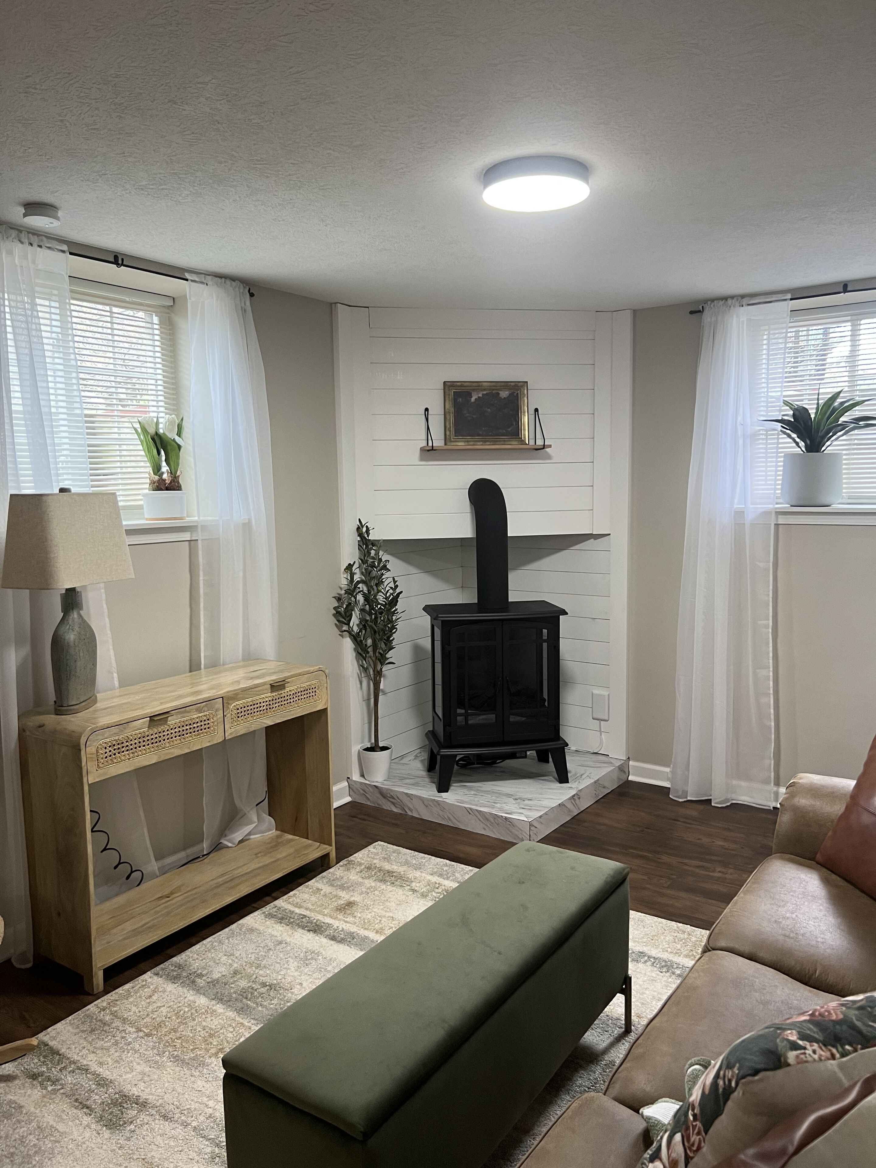 A cozy living room with a fireplace, a wooden console table, a green bench, and a leather sofa.