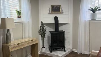 A cozy living room with a fireplace, a wooden console table, a green bench, and a leather sofa.