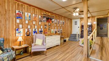 A room with wooden walls, a ceiling fan, a staircase, and a wall of framed pictures.