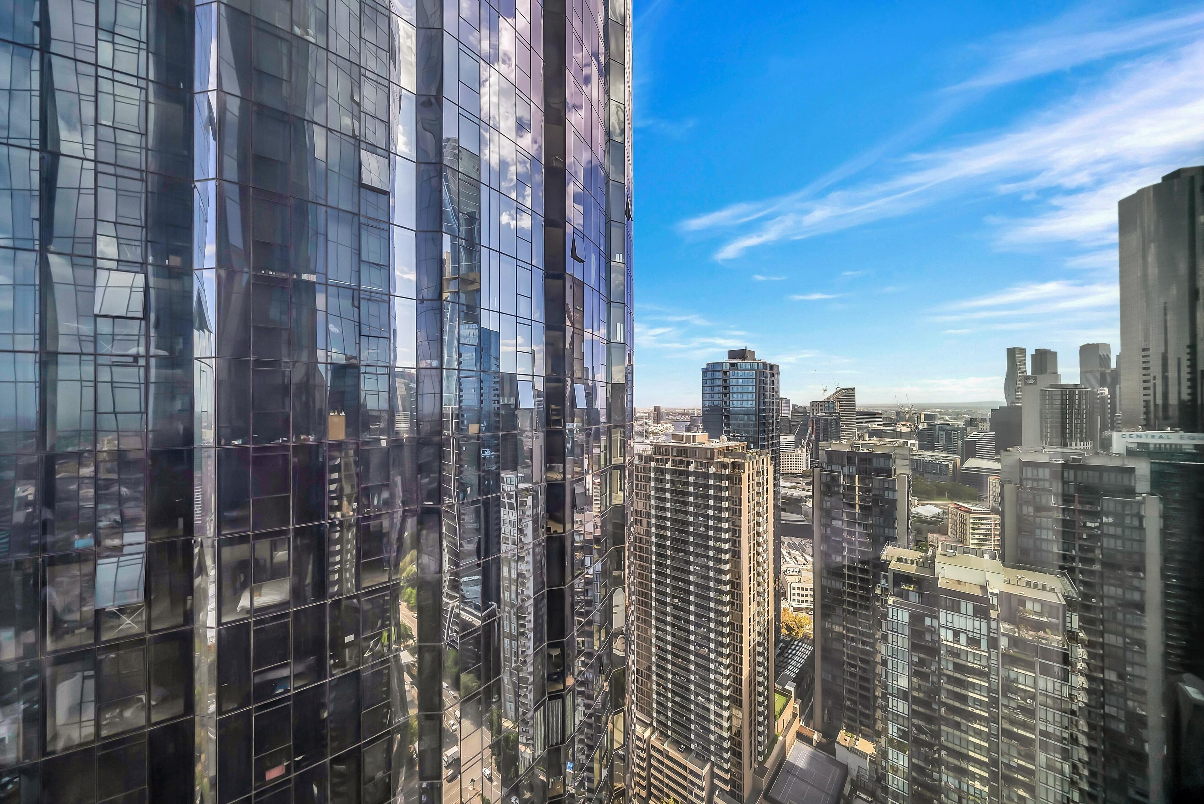 Un immeuble de grande hauteur doté d’une façade moderne en verre, entouré d’autres bâtiments imposants au cœur d’un paysage urbain.