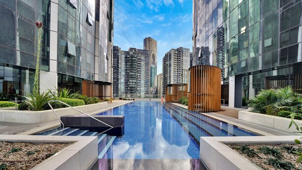 A modern residential building with a central swimming pool, surrounded by greenery and high-rise buildings. - Melbourne Square Apartments (Southbank)
