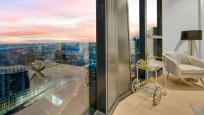 A high-rise room with a city view, a glass table with a gold base, and a white armchair. - Melbourne Square Apartments (Southbank)