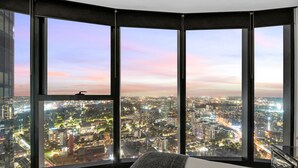A high-rise hotel room with a panoramic city view through large windows. - Melbourne Square Apartments (Southbank)