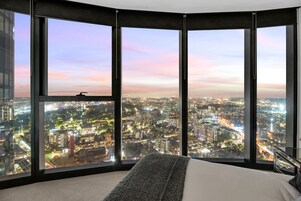 Habitación de hotel en un rascacielos con amplias ventanas y una vista panorámica de la ciudad.