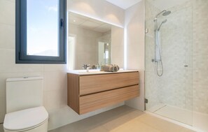 A modern bathroom with a toilet, a vanity with a mirror, and a walk-in shower. - Gorgeous apartment in Estepona with swimming pool (Estepona)