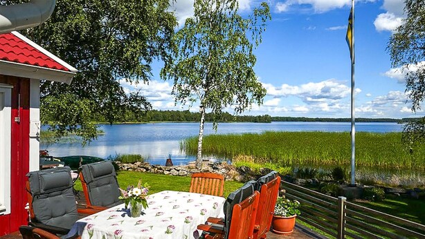 An outdoor deck with a table and chairs, overlooking a lake and a field. - Awesome home in Värnamo with kitchen (Värnamo)