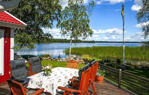 Une terrasse extérieure avec une table et des chaises, donnant sur un lac et un champ.