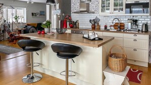 A modern kitchen with a central island, bar stools, and a dining area with a sofa and chairs. - Awesome home in Värnamo with kitchen (Värnamo)