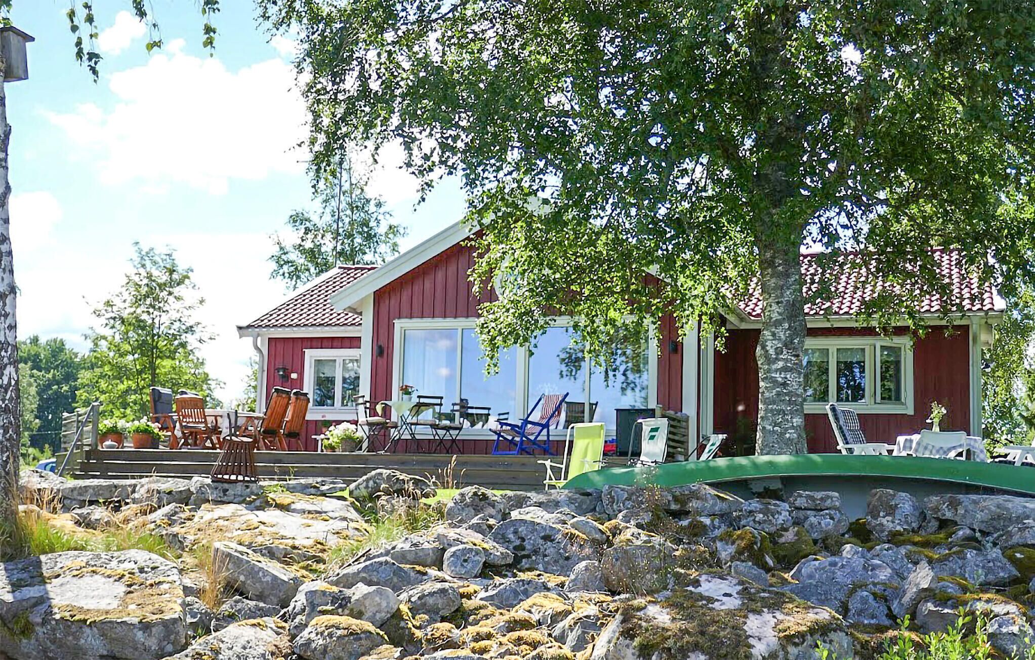 A red wooden house with a porch, outdoor seating, and a stone wall in front.