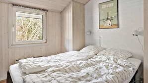 A bedroom with a bed, a window, a wall-mounted lamp, and a poster of a windmill. - Nice home in Nørre Nebel with sauna (Nørre Nebel)
