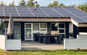 A house with a solar panel roof, a patio with outdoor furniture, and a covered area with a grill. - Nice home in Nørre Nebel with sauna (Nørre Nebel)