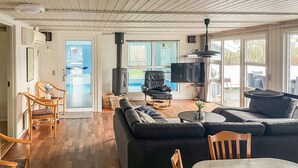 A living room with a sofa, chairs, a TV, a fireplace, and a view of the outside. - Nice home in Nørre Nebel with sauna (Nørre Nebel)