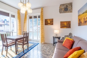 Un salon comprenant une table à manger, des chaises, un canapé, une lampe et des œuvres d’art accrochées aux murs.